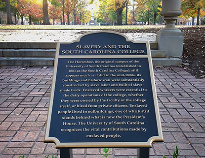Plaque at the top of the horseshoe acknowledging the contribution of enslaved people building the original University of South Carolina campus. It says "Slavery and the South Carolina College. The horseshoe, the original campus of the University of South Carolina (established in 1801 as the South Carolina College), still appears much as it did in the mid-1800s Its buildings and historic wall were substantially constructed by slave labor and built of slave-made brick. Enslaved workers were essential to the daily operations of the college, whether they were owned by the faculty or the college itself, or hired from private citizens. Enslaved people lived in outbuildings, one of which still stands behind what is now the President's House. The University of South Carolina recognizes the vital contributions made by enslaved people." 