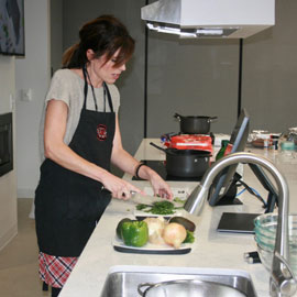 Cooking class instructor, Lindsay Shazly, dicing cilantro in a demonstration kitchen
