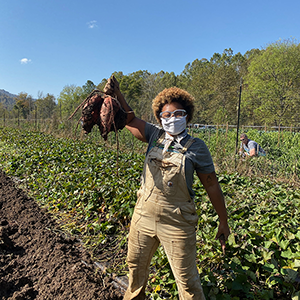 sustainable carolina garden manager sadia pollard holds up vegetables harvested from a garden